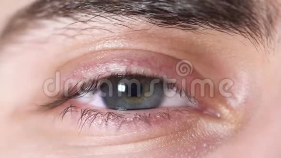人类眼睛的特写年轻男子美丽的眼睛瞳孔从光中缩小人眼灰褐色有阴影视频的预览图