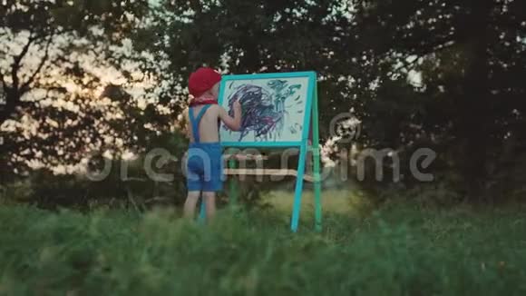 小男孩站在公园的画架上画画视频的预览图