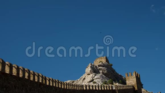 黑色的乌鸦飞过悬崖顶的堡垒塔在阳光明媚的夏日视频的预览图