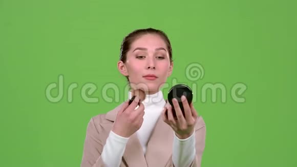 女孩被涂上油漆用刷子放粉然后照镜子绿色屏幕视频的预览图