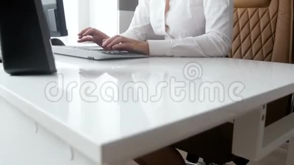 4K画面美丽的微笑女商人坐在现代的白色办公桌后面用电脑工作视频的预览图