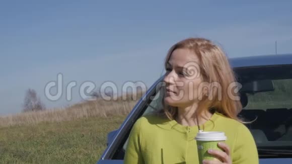 自信的年轻商务女性在农村公路上的汽车附近喝着咖啡慢动作视频的预览图