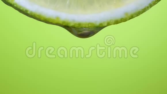 鲜片石灰一滴水落这种水果散发出新鲜感和果汁绿色背景视频的预览图