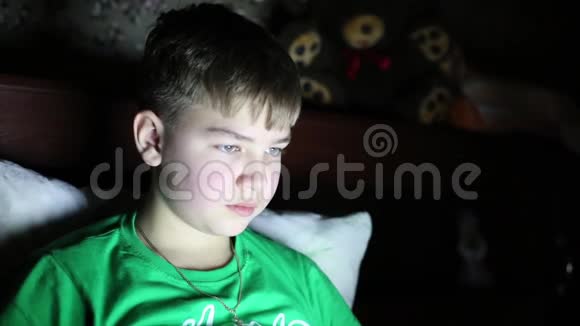一个少年在黑暗的房间里玩电脑游戏视频的预览图