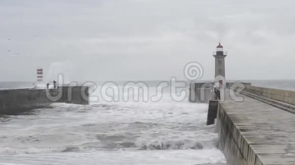 在有灯塔的防波堤码头观看风暴海洋的人们视频的预览图