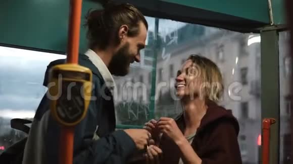 年轻漂亮的男人和女人互相喂糖果或糖果玩得很开心在电车里快乐的一对视频的预览图