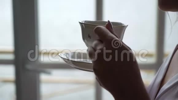 年轻女子早上从杯子里喝咖啡家庭早餐视频的预览图