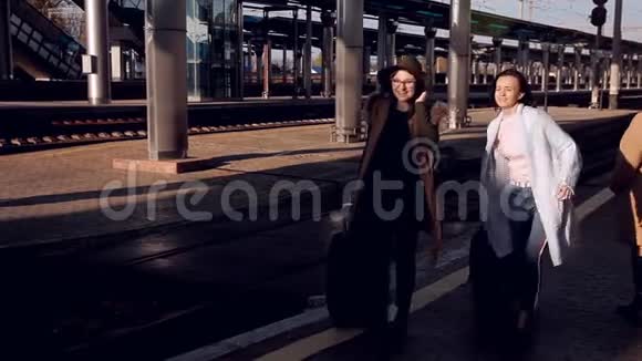 火车站的两个女孩提着手提箱站在站台上等火车视频的预览图