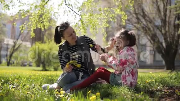 母亲在公园为女儿织了一个蒲公英花圈视频的预览图
