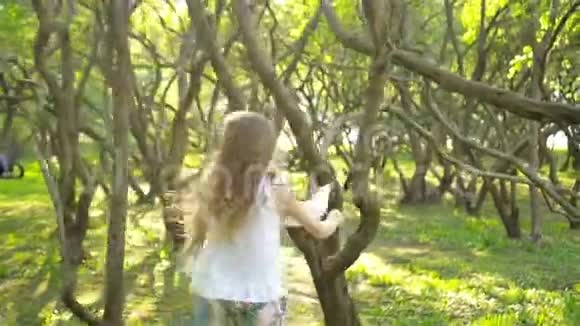 可爱的女孩在盛开的苹果树花园享受温暖的一天视频的预览图