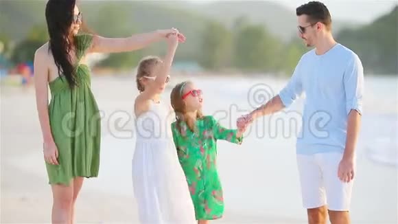 父母和可爱的两个孩子在海滩上的暑假里玩得很开心四口之家相爱开心快乐视频的预览图