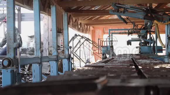 钢盔木工在工业锯工作台上卸下木块视频的预览图