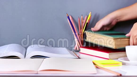 女人把精装书和课本叠在木桌上视频的预览图