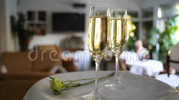带有戒指的玻璃底部放在白色托盘上的香槟中在浪漫的活动中没有聚焦的背景上放小花视频的预览图