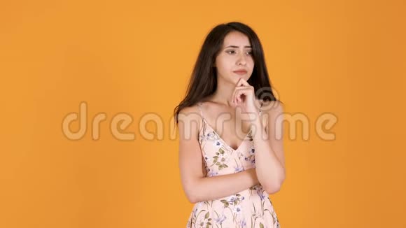 一个美丽的女孩在橙色黄色的背景下思考视频的预览图