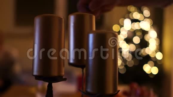 男性手点燃蜡烛用模糊的圣诞灯光背景关闭三支蜡烛视频的预览图