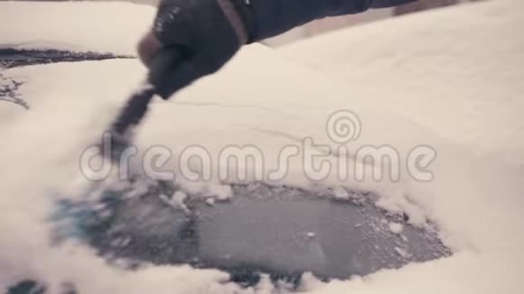 一个年轻人从雪中清洁汽车的窗户视频的预览图