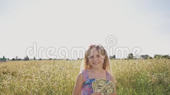 在一个温暖的阳光明媚的日子里小女孩在大自然的背景下扔美元钞票金钱财务和人的概念视频的预览图