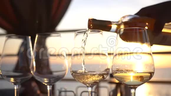 日落时将白葡萄酒倒在透明玻璃杯上高清1920x1080慢动作视频的预览图