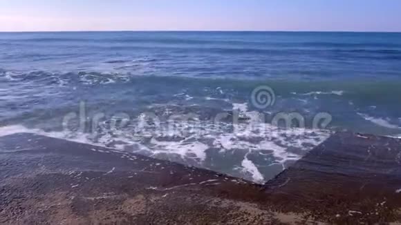 汹涌的海浪溅起水面在海滨的防波堤上哗哗作响蓝天视频的预览图