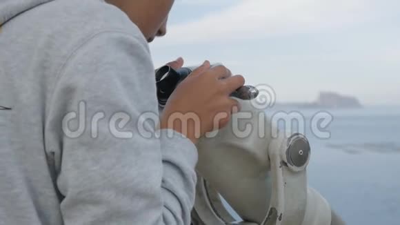 近距离拍摄的少年望着大海从高高的观景台进入望远镜视频的预览图