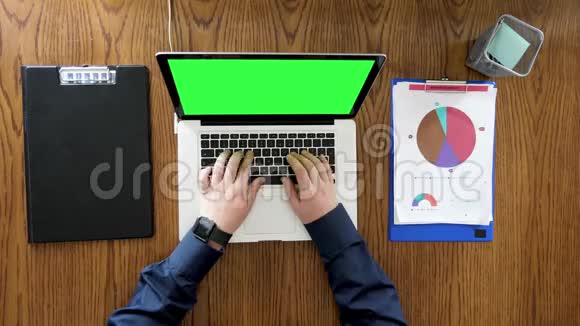 商人手在带有绿色屏幕的笔记本电脑上打字和滚动视频的预览图