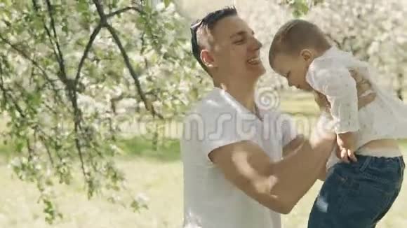 父亲把孩子抱在怀里然后吐出来年轻的父子在户外玩得很开心视频的预览图