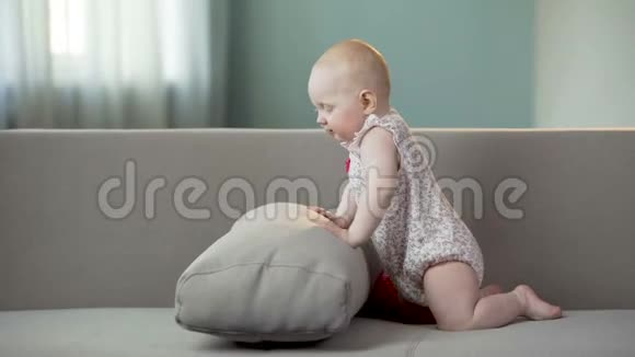 玩耍的女婴在家里的沙发上玩耍活跃的婴儿发现世界视频的预览图