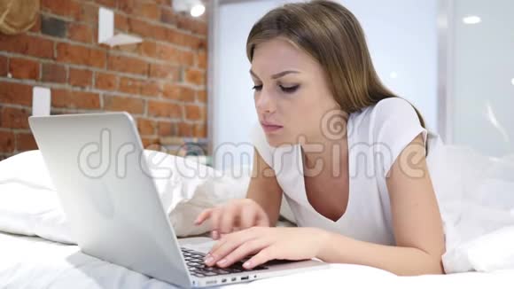 在床上工作的妇女在笔记本电脑上工作并应对损失失败视频的预览图