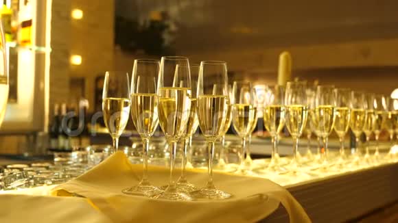 托盘上放着四杯香槟的酒杯带着服务员一杯香槟放在白色的桌子上很多带眼镜的视频的预览图