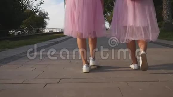 两条穿薄纱裙子的女士腿和户外行走的运动鞋视频的预览图