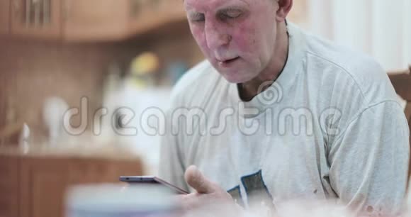 老人用智能手机低着头看着他视频的预览图