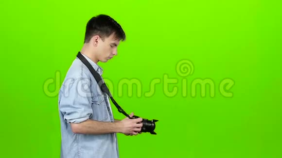 盖伊在专业摄像机上拍摄风景绿色屏幕慢动作视频的预览图
