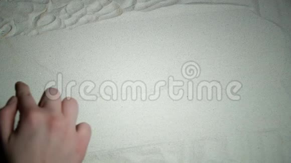 女人的手在沙子上写着沙子这个词视频的预览图