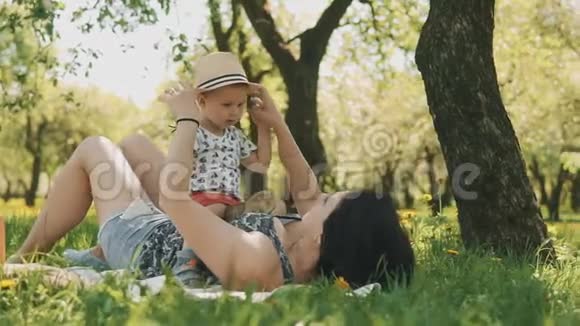 快乐的微笑妈妈和可爱的儿子在大树下野餐家庭概念视频的预览图