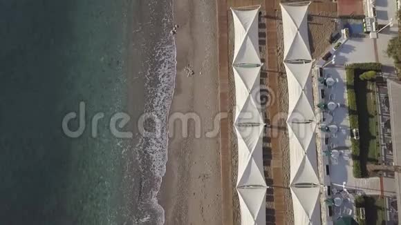 沙滩上有雨伞的海岸线的空中镜头视频的预览图