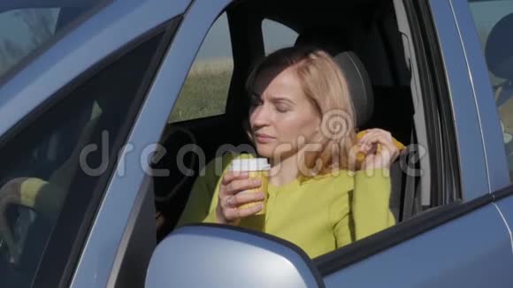 自信的年轻女人在汽车的车轮上喝咖啡慢动作视频的预览图