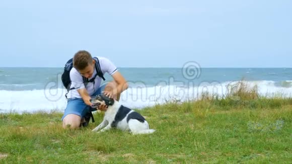 一个年轻人和一只狗沿着海岸散步视频的预览图