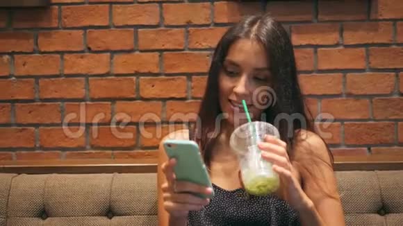 年轻迷人的女孩在咖啡厅喝抹茶在手机上发短信4K泰国视频的预览图