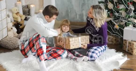 幸福的家庭坐在地板上拿着圣诞礼物一个孩子享受圣诞礼物视频的预览图