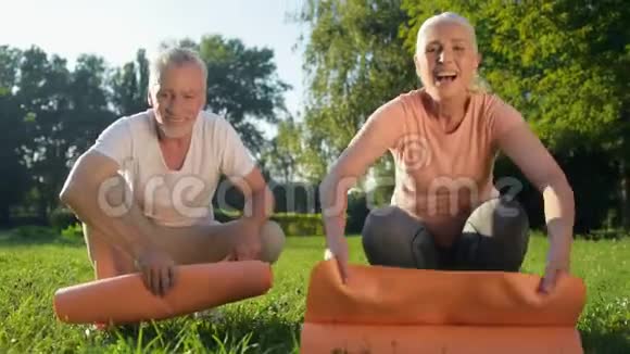 快乐的老夫妇在草地上滚动他们的运动垫视频的预览图