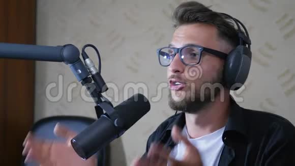 男子收音机主持人眼镜和耳机在录音室对着迈克说视频的预览图