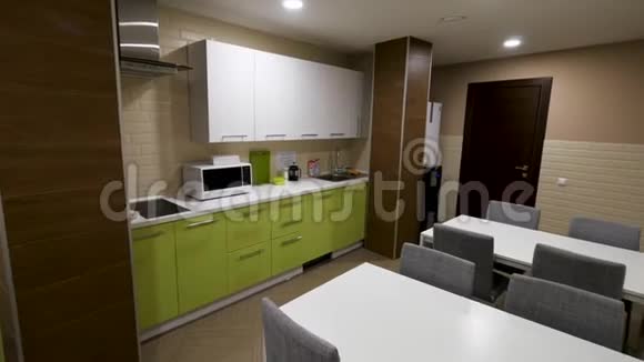 小的现代化的厨房有绿色的橱柜和两张桌子为上班族提供饮食区简单小新绿色视频的预览图
