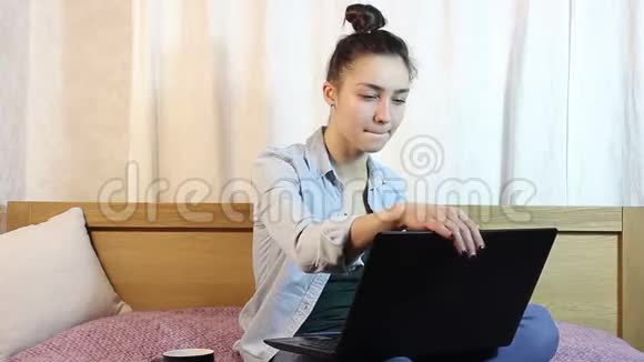 一个年轻漂亮的女孩从她的笔记本电脑工作同时喝咖啡从一个黑色的杯子视频的预览图