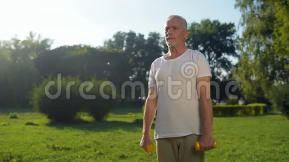 运动的老人在公园里用哑铃锻炼身体视频的预览图
