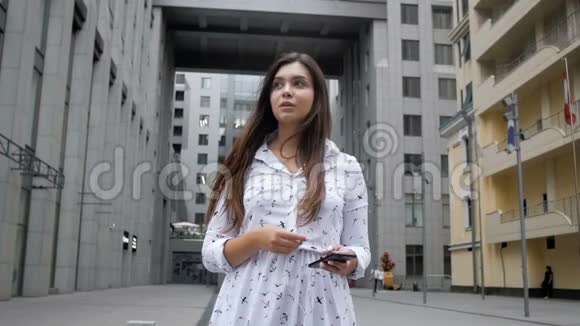 慢动作视频忧心忡忡的年轻女子走在街上拿着手机视频的预览图