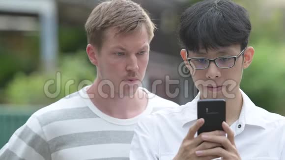 两个多民族的商人在户外的街道上一起使用电话视频的预览图