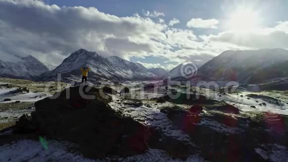 孤独的登山者在云层上方的雪山上休息进入太阳登山者到达雪山的顶端视频的预览图