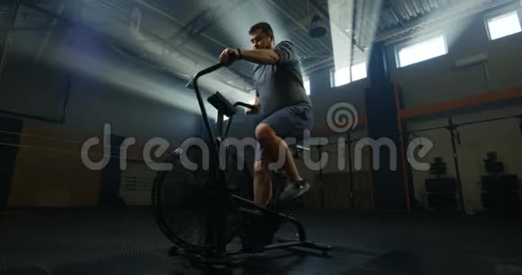 超重的年轻人骑着运动自行车运动视频的预览图