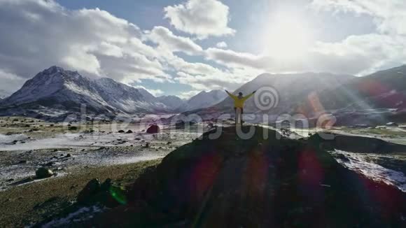孤独的登山者在云层上方的雪山上休息进入太阳登山者到达雪山的顶端视频的预览图